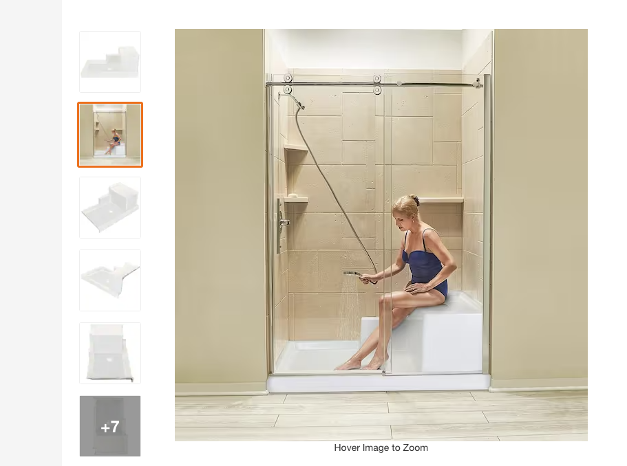 Image from my google search of a woman sitting on a seat in the back of a shower bathing with a bathing suit on. She is holding a handheld shower head and is at least two feet or more from the front of the shower.